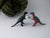 
          
            two tiny dinosaur toys holding a silver knitting needle gauge ring in front of handspun yarn
          
        