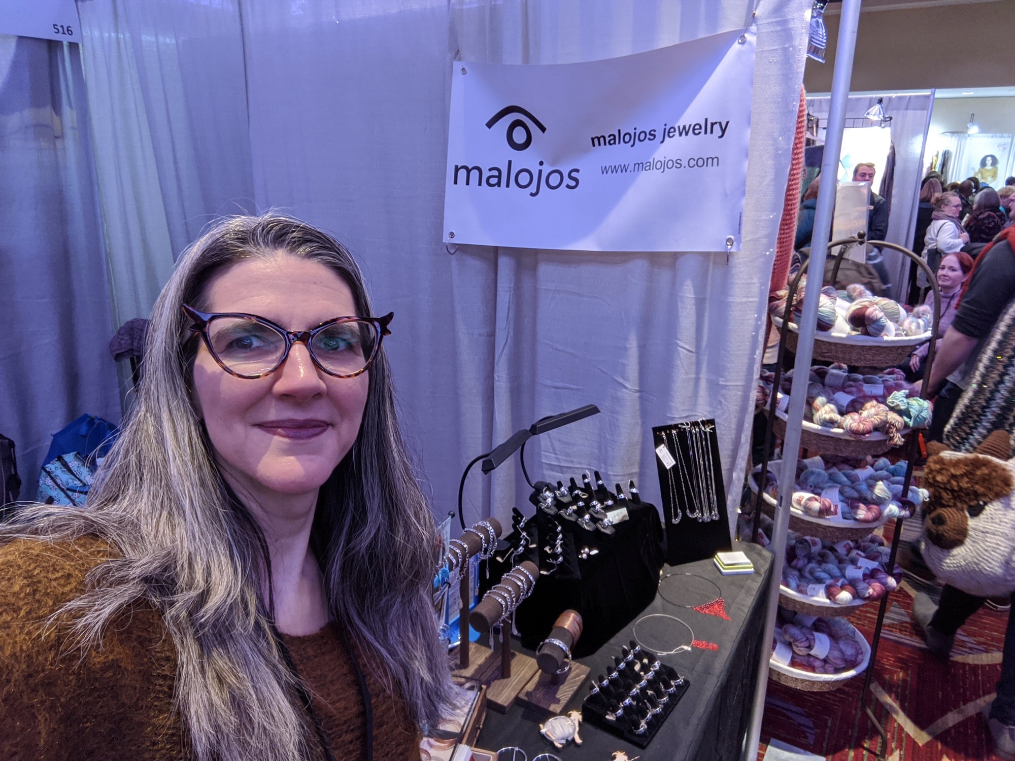 
          
            Natalia next to her Malojos booth at Vogue Knitting Live NYC
          
        